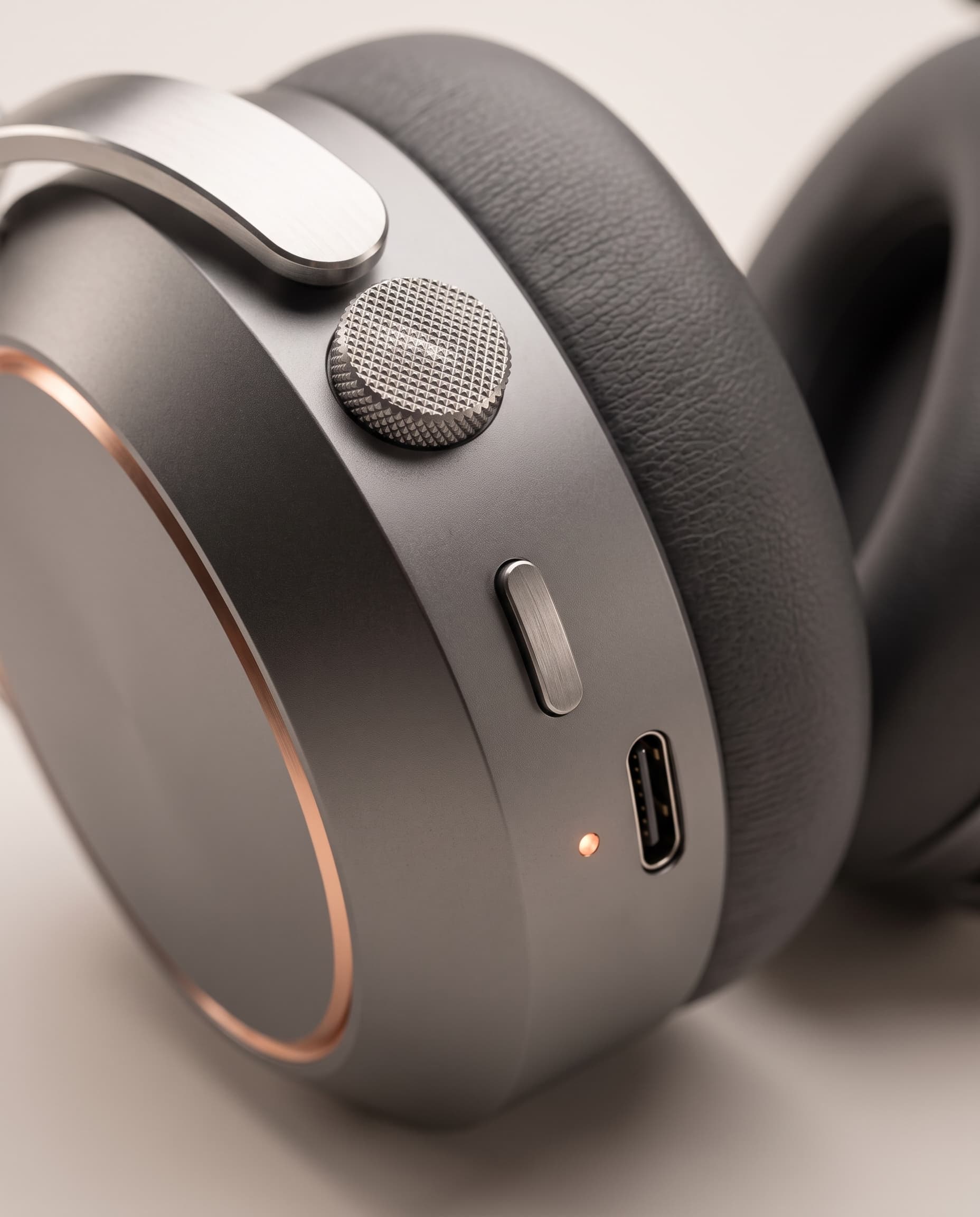 Macro view of the knurled steel crown, mode button, status light and USB-C port on the right earcup